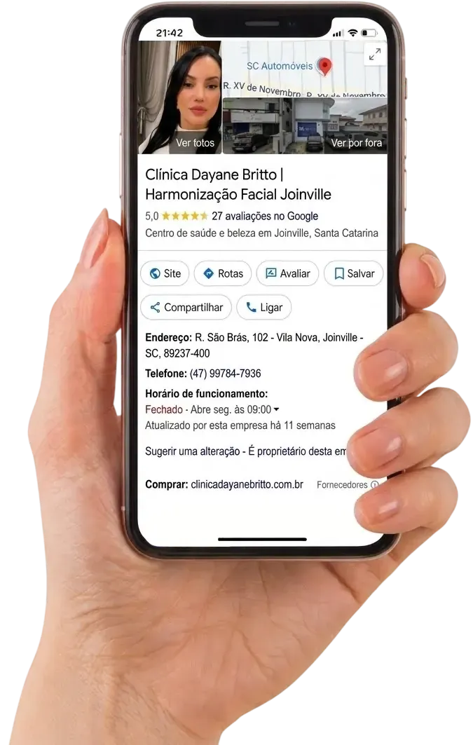 Mão segurando um celular que exibe o perfil de uma clínica no Google Meu Negócio, com nota, avaliações, endereço e botões de ligar e traçar rota