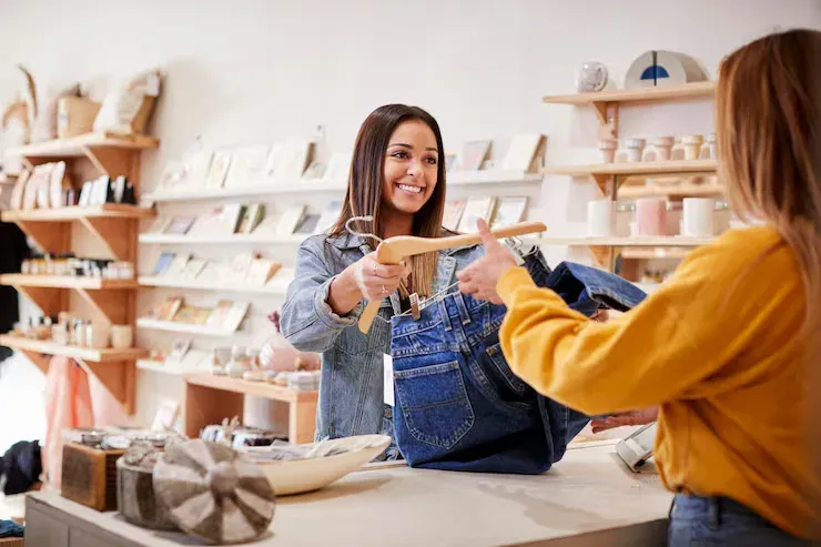Lojista sorrindo ao atender uma cliente no balcão da loja, que ganha clientes pelo Google Maps da sua região